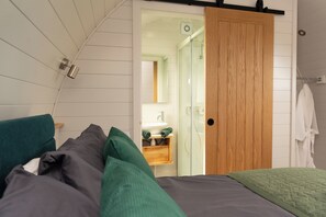 Un dormitorio con una cama, una puerta de madera y un baño visible a través de una puerta abierta.