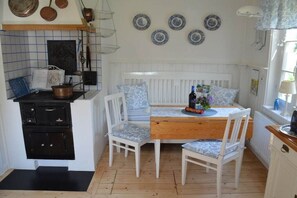 A kitchen with a white bench, a wooden table, and a stove. - Holiday home with 2 bedrooms (Mariannelund)