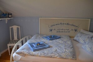 Ein Schlafzimmer mit einem Bett, einem Kopfende mit einer dekorativen Aufschrift und einem Sessel.