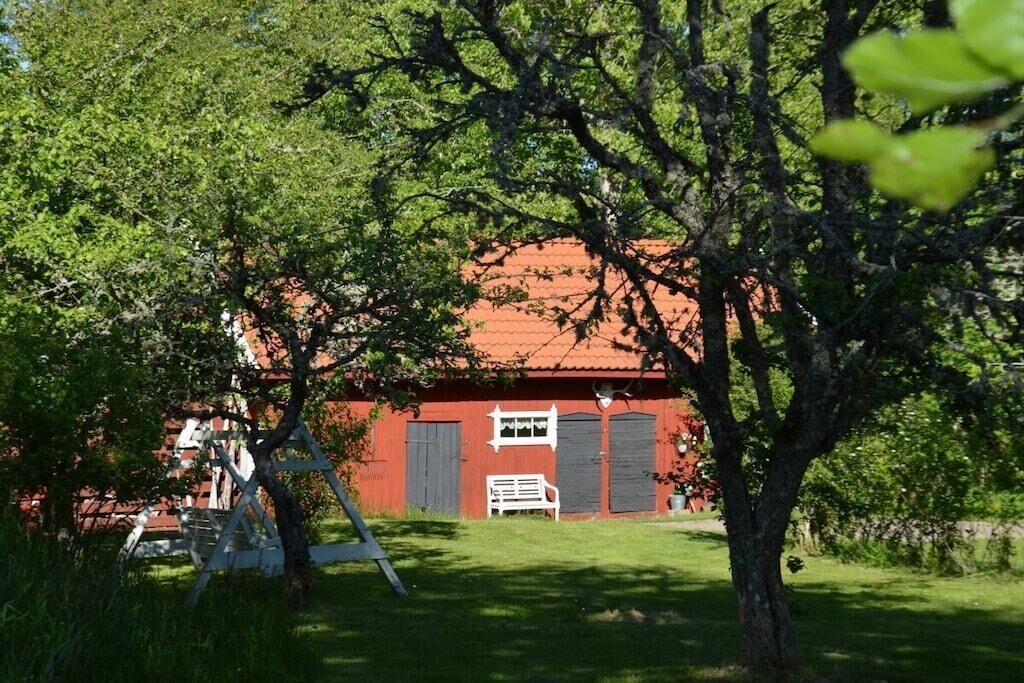 Een rood gebouw met een witte bank en een schommel op een gazon.