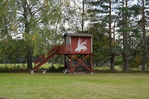 A red lookout tower with a white eagle design, surrounded by trees. - Holiday home with 2 bedrooms (Mariannelund)