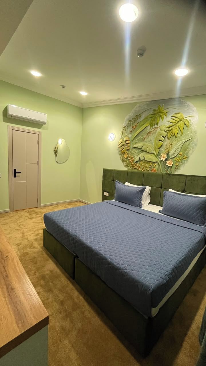 Una camera da letto con un letto, una scrivania in legno, un condizionatore d'aria a parete e una porta.