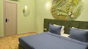 A bedroom with a bed, a wooden desk, a wall-mounted air conditioner, and a door.