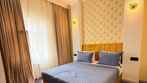 Un dormitorio con una cama grande, cabecera, luz empotrada en la pared y ventana con cortinas.