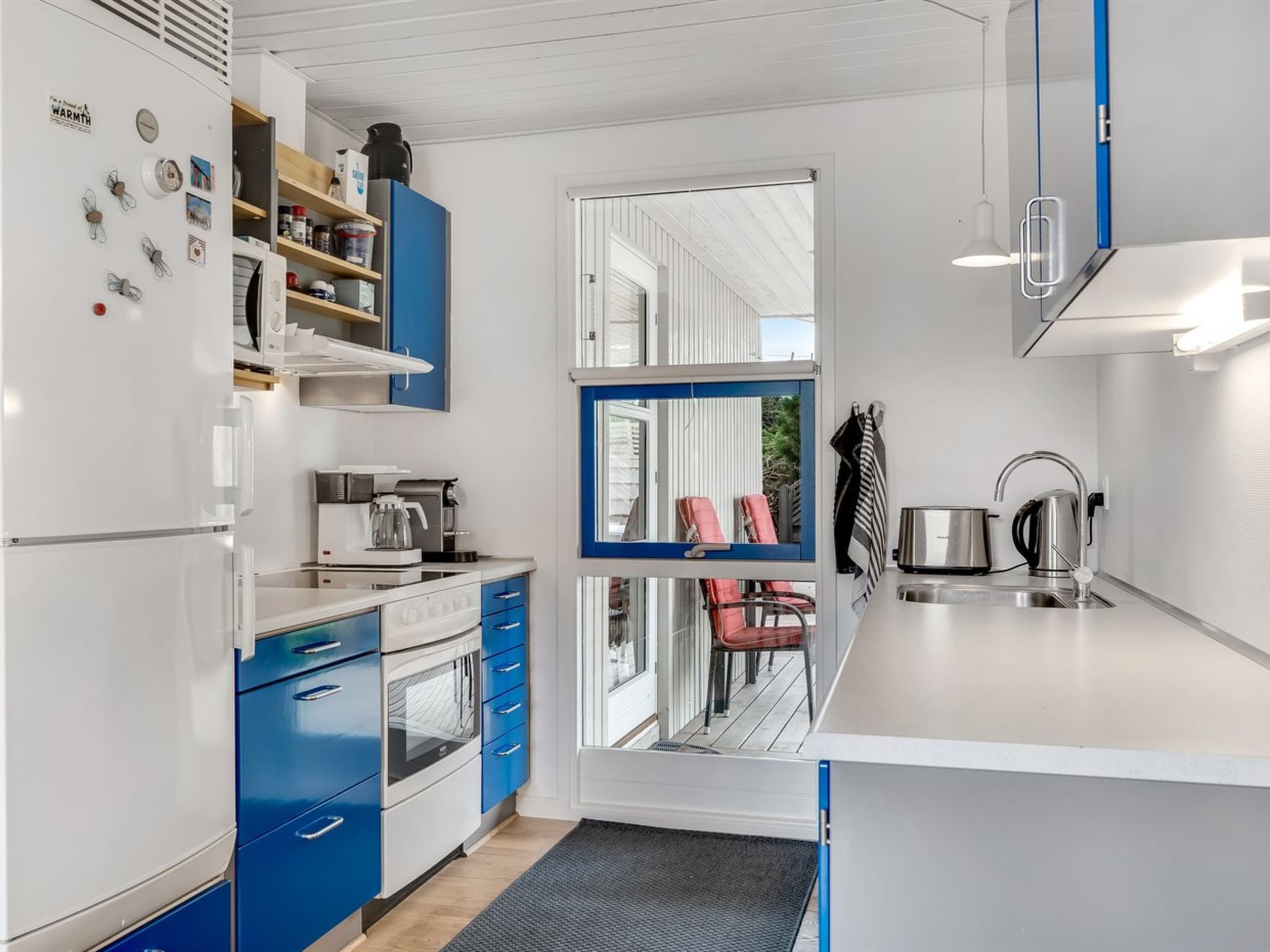 Een moderne keuken met blauwe kastjes, een inbouwoven en een koffiezetapparaat.