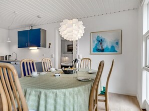 A dining area with a table set for four, surrounded by wooden chairs, a hanging light fixture, and a painting on the wall. - "Jale" - 300m from the sea by Interhome (Thisted)
