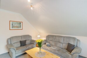 A living room with two grey sofas, a wooden coffee table, and a vase with yellow flowers.