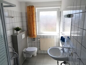 A modern bathroom with a toilet, sink, and shower. - Apartment 'Haus Hanning 2' with Shared Garden and Wi-Fi (Wangerland)