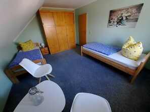 A small, cozy room with a bed, a chair, a table, and a wardrobe. - Apartment 'Haus Hanning 2' with Shared Garden and Wi-Fi (Wangerland)