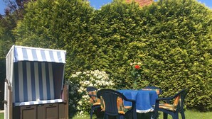 Ein Garten mit Streifenmarkise und Gartenmöbeln.