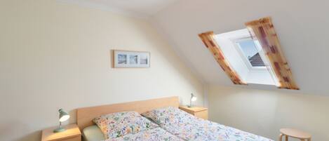 A bedroom with a bed, bedside tables, a window, and a ceiling light.