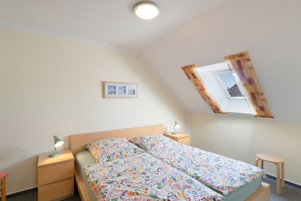 A bedroom with a bed, bedside tables, a window, and a ceiling light.