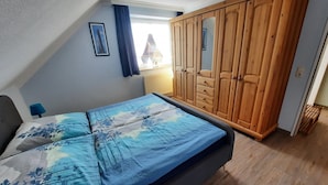 Ein Schlafzimmer mit einem Bett, einem Holzschrank und einem Fenster mit Vorhängen.