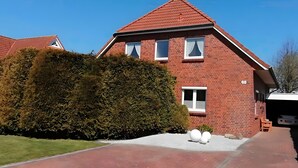 Ein rotbackenförmiges Haus mit einem geneigten Dach, einem gepflegten Rasen und einer Auffahrt zum Eingang.