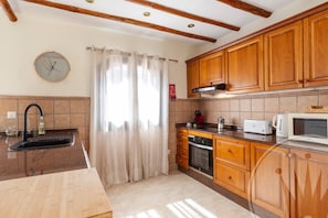 Una cocina con armarios de madera, un fregadero, una estufa y un microondas.