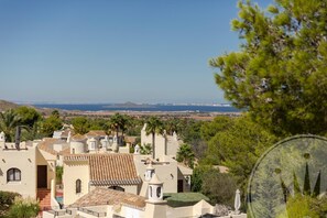 Eine Küstenstadt mit Gebäuden im mediterranen Stil, freiem Blick auf das Meer und üppiger Vegetation.