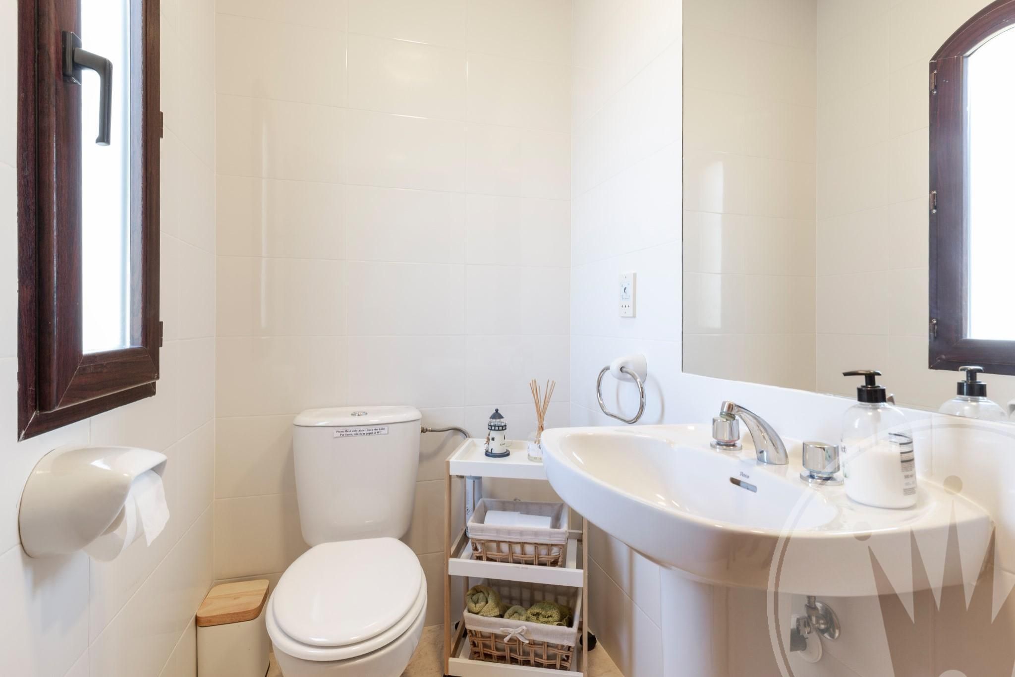 Un baño con inodoro, lavabo, espejo y ventana.
