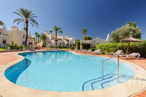 Ein Swimmingpool mit Liegestühlen und Palmen.