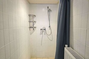 A small, tiled shower area with a handheld showerhead and a wall-mounted faucet. - Holiday home with 2 bedrooms (Oostkapelle)