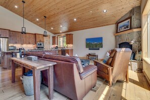 Eine moderne Küche mit Holzausstattung, ein Essbereich mit Ledersofa und ein Kamin aus Stein.