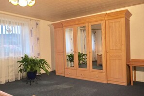 Ein Zimmer mit einem großen Holzschrank, einem kleinen Tisch und zwei Blumentöpfen.