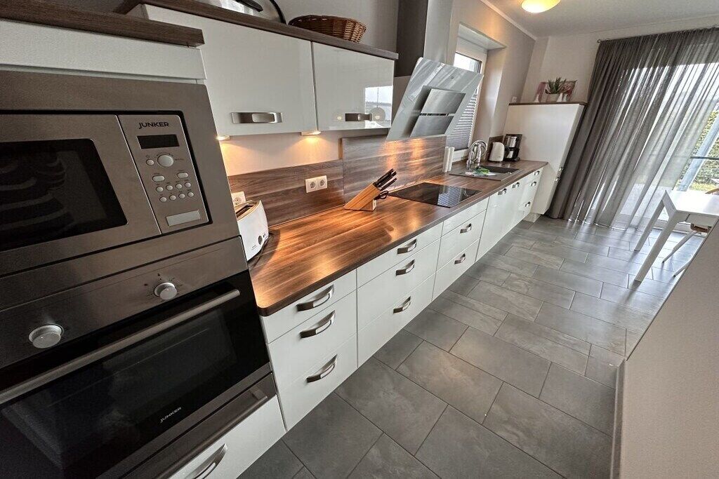 Una cocina moderna con microondas integrado, horno y electrodomésticos de acero inoxidable.