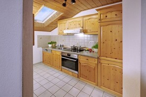Eine Küche mit Holzschränken, einem Herd und einem Oberlicht.