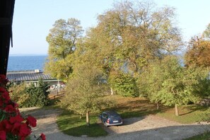 Ein Kiesweg führt zu einem geparkten Auto, umgeben von Bäumen und einem Gebäude mit einem geneigten Dach.