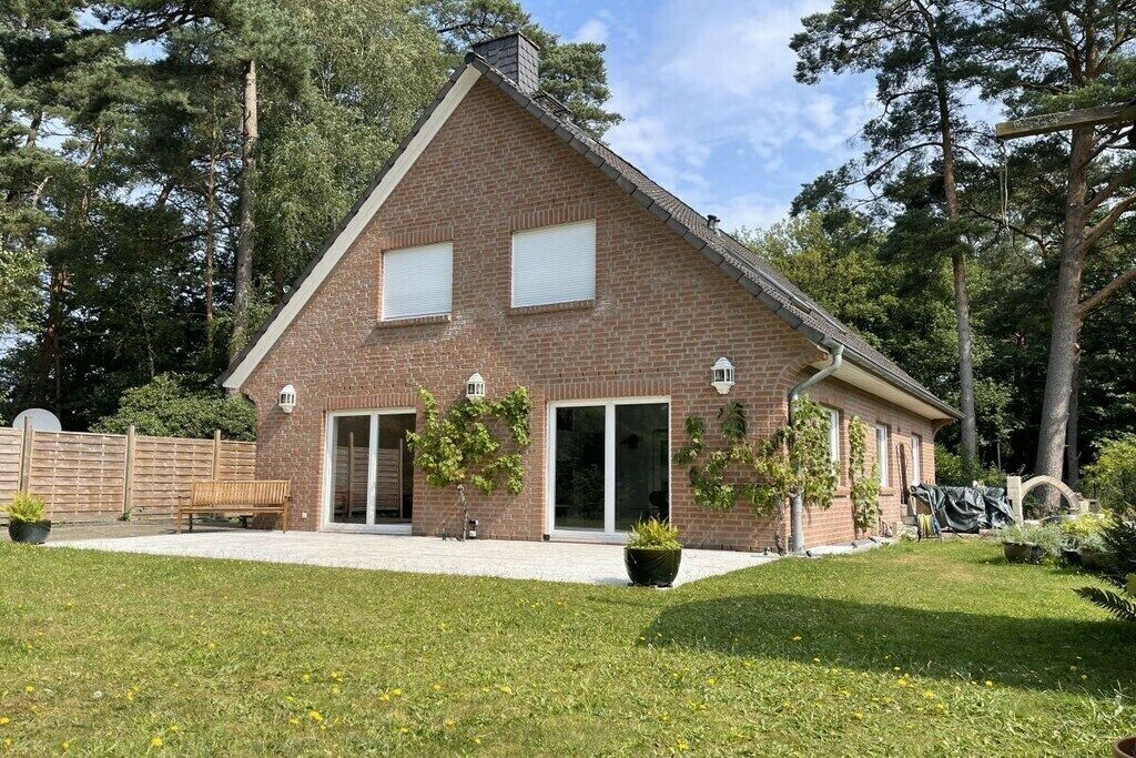 Une maison en briques avec un toit en pente, de grandes fenêtres et un patio couvert.