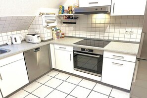 Une cuisine compacte équipée d’un lave-vaisselle, d’un grille-pain, d’un four et d’un petit plan de travail avec une bouilloire.