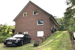 A two-story brick house with a car parked in front. - Forest holiday apartment Hamburg 1 (Rosengarten)
