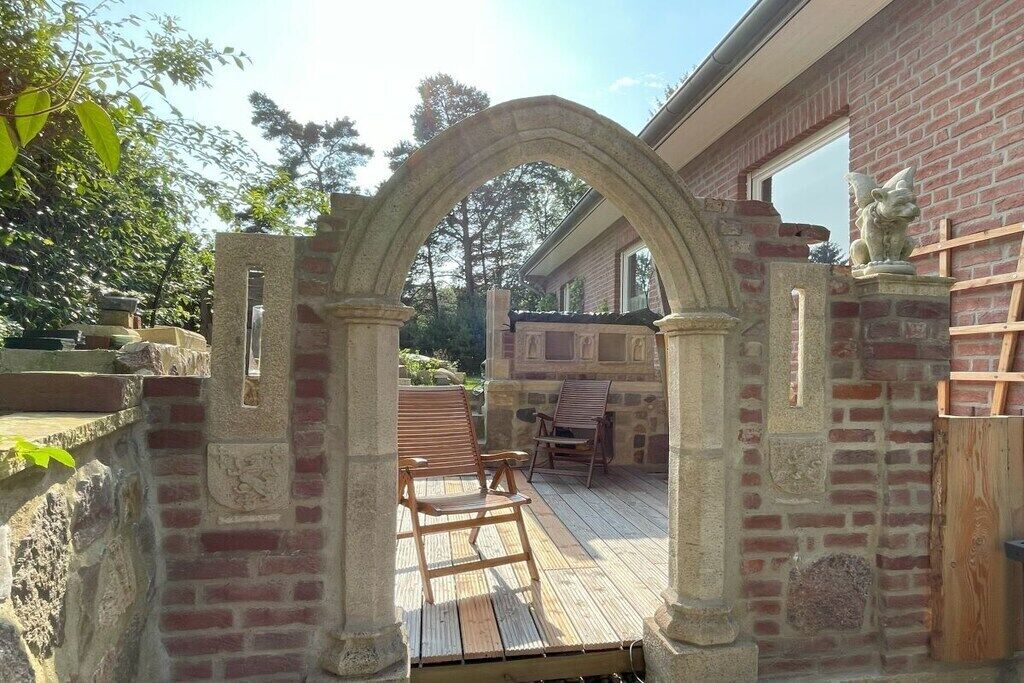 A stone archway leading to a wooden deck with outdoor furniture.