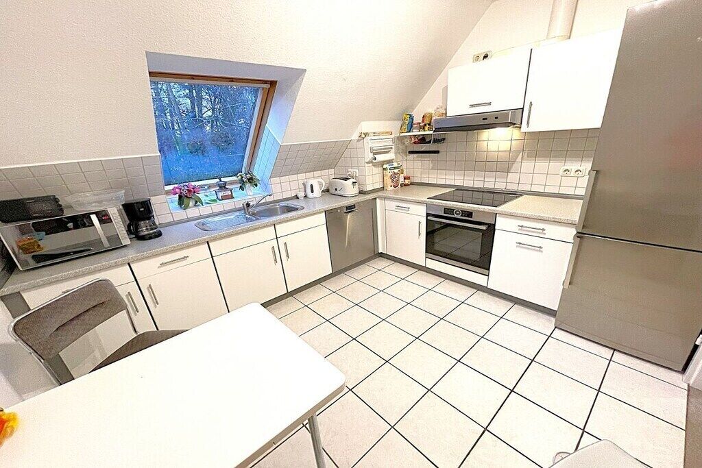 Una cocina compacta con armarios blancos, un microondas, una estufa y un fregadero.