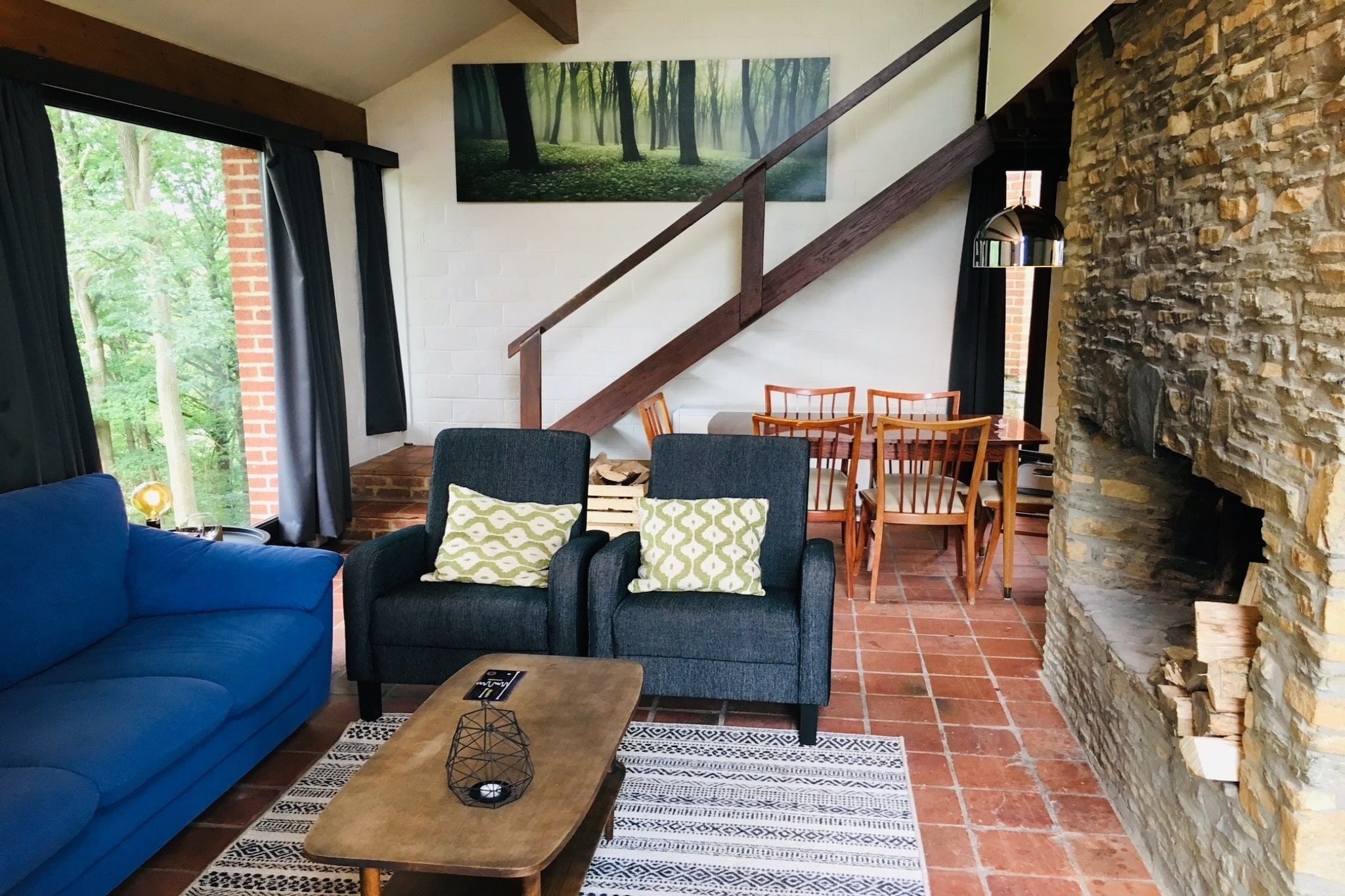 A cozy living room with a blue sofa, two armchairs, a coffee table, and a fireplace.