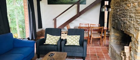 A cozy living room with a blue sofa, two armchairs, a coffee table, and a fireplace.