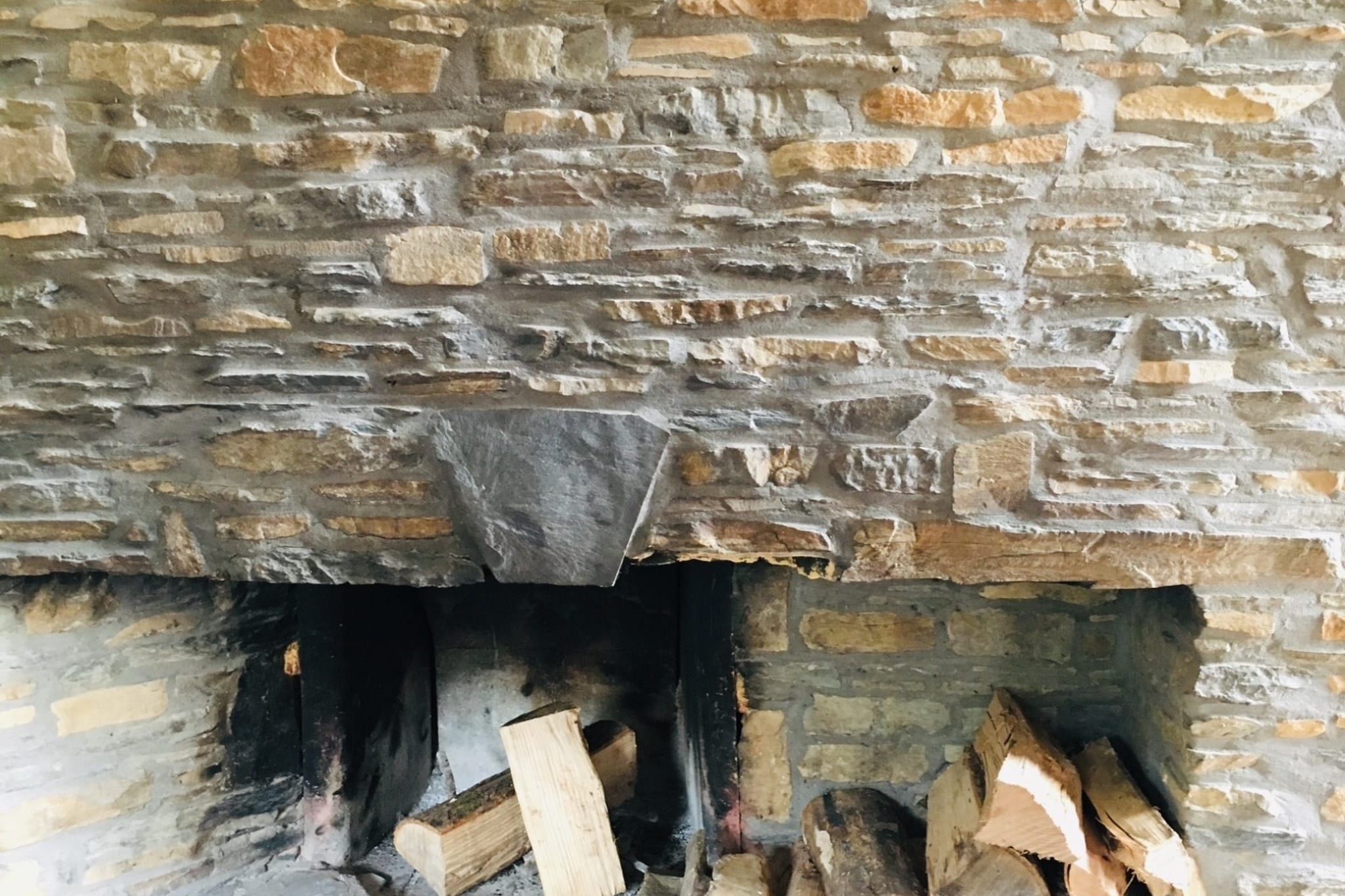 A stone fireplace with logs.
