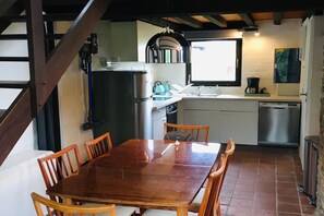 A compact kitchen with a dining table and chairs, a refrigerator, a sink, and a window. - Charming holiday home with a beautiful view (Blaimont)