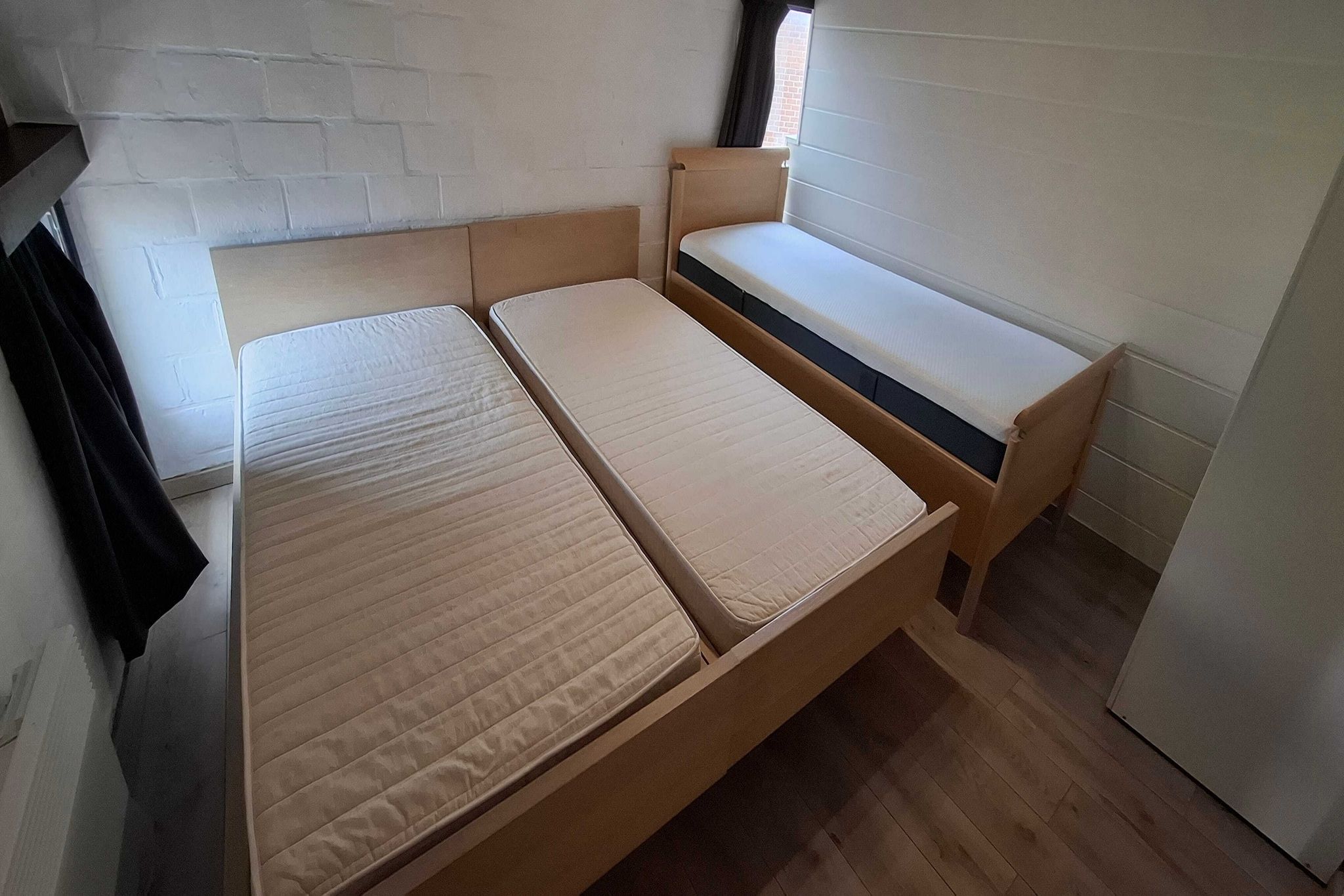 Une pièce avec un lit, un banc et une fenêtre.