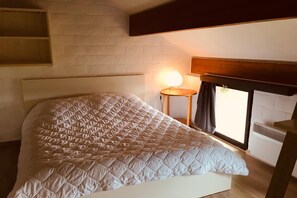 A bed with a quilted headboard, a bedside lamp, and a window with curtains. - Charming holiday home with a beautiful view (Blaimont)