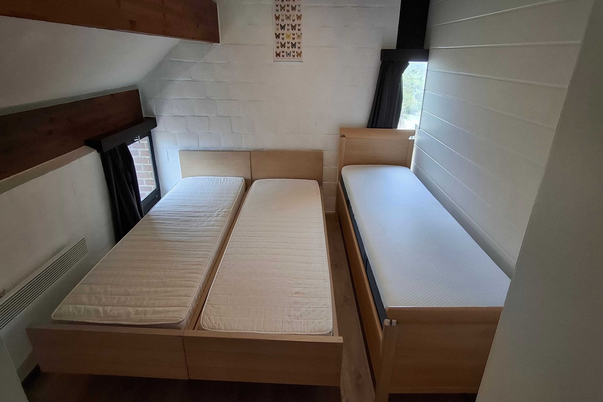 A room with two beds, a window, and a wall-mounted butterfly art piece.