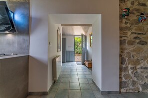 A hallway with a radiator, a door leading outside, and a stone wall with masks.
