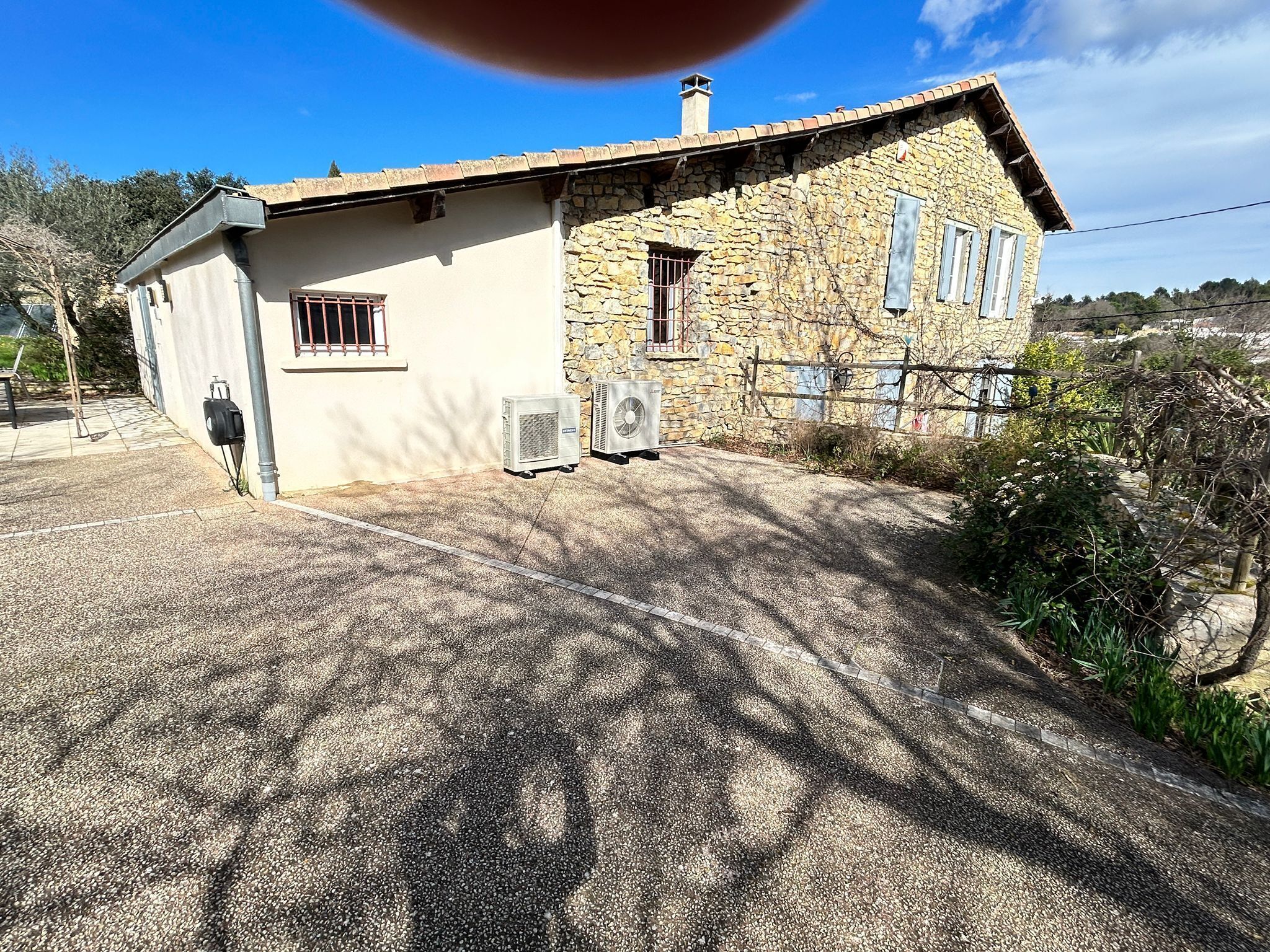 A stone building with a sloped roof, a small attached structure, and two air conditioning units.