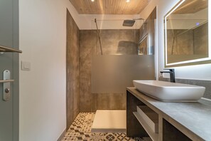 Ein modernes Badezimmer mit einem großen Spiegel, einem Aufsatzwaschbecken und einer Dusche.