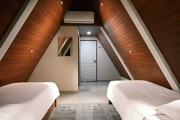 A bedroom with two beds, a ceiling fan, and a door leading to another room.