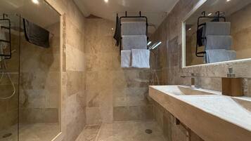 Un baño moderno con cabina de ducha de vidrio, un espejo grande y encimera de mármol.