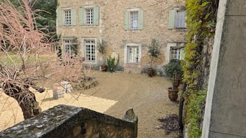 Un bâtiment en pierre doté de nombreuses fenêtres et d’une cour recouverte de gravier.