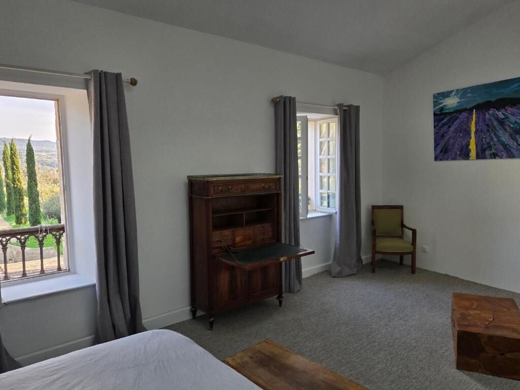 A room with a bed, a wooden cabinet, a chair, and a painting on the wall.