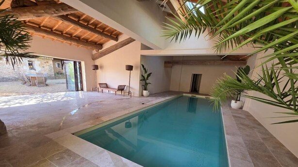 An indoor swimming pool with a tiled floor, surrounded by walls and potted plants. - Bastide du Luberon (APT)
