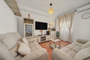 A living room with two sofas, a TV, a table, and a ceiling light.