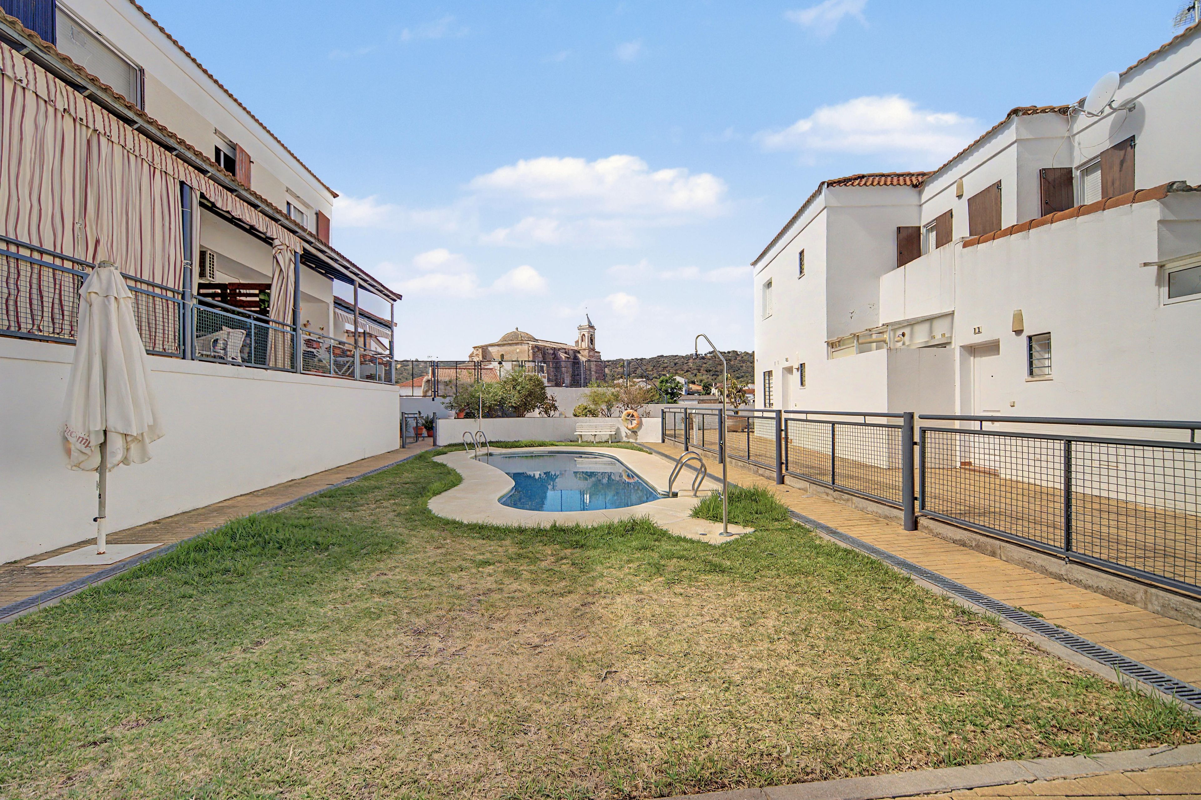 A residential area with a swimming pool, a church in the background, and a white building with a balcony.